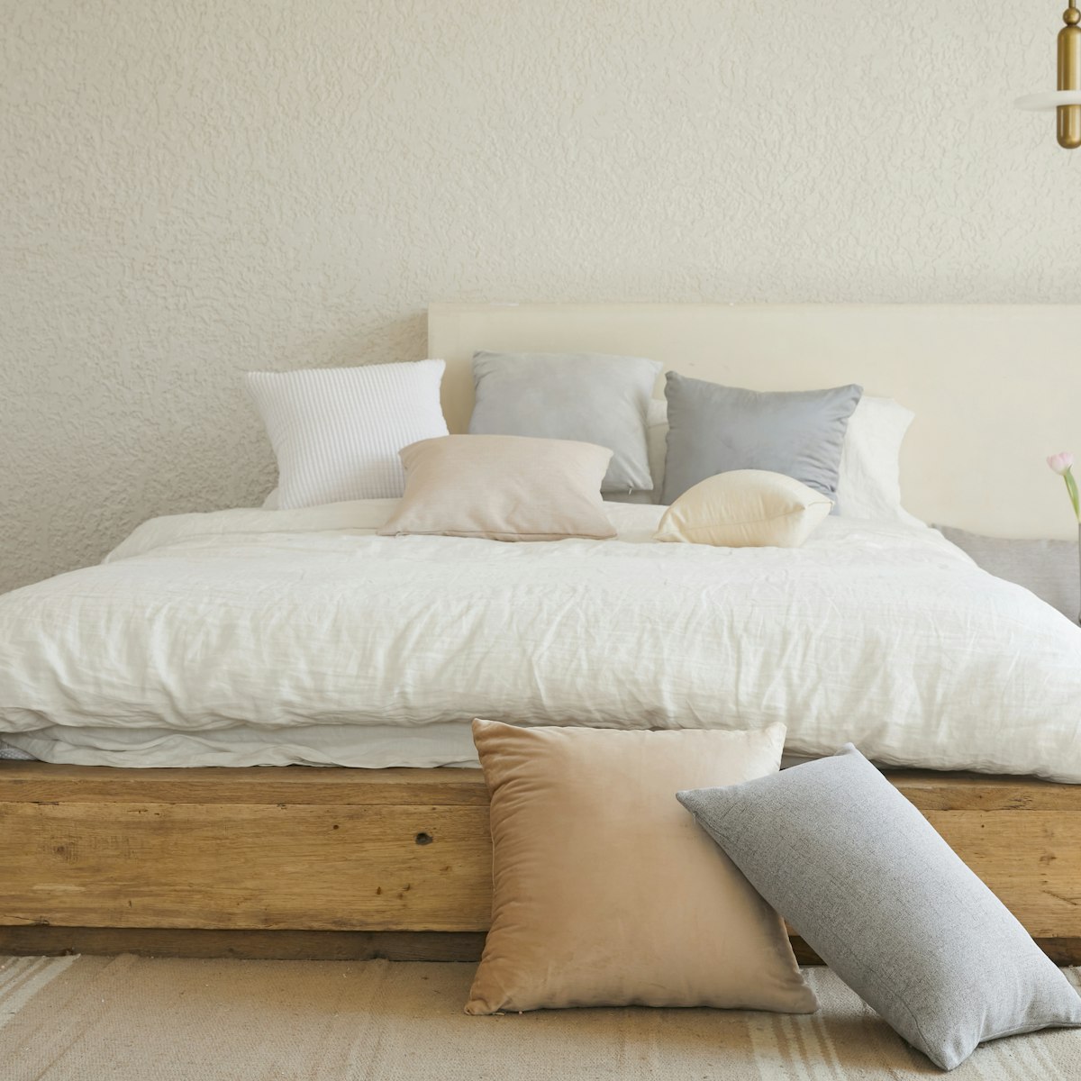 Low platform bed made from reclaimed wood with white bedding
